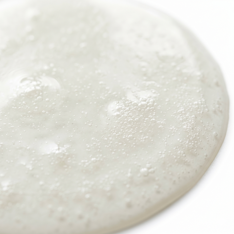 Close-up of cloudy white pool of AEA certified emu oil on a white background